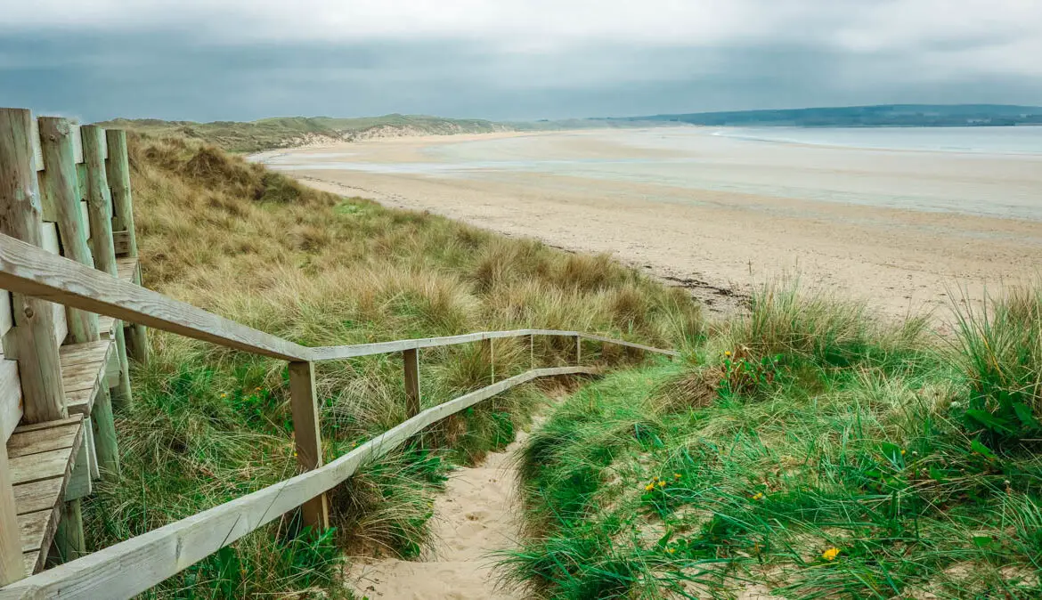 Schottland Rundreise, Blick auf einen einsamen, lang gezogenen Strand, mit grünem Gras