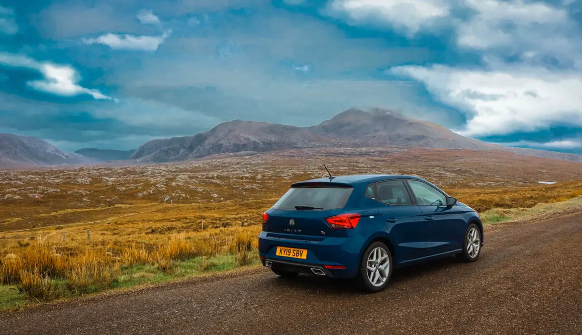 Schottland Roadtrip, Auto auf einer Straße durch schottische Hügellandschaft