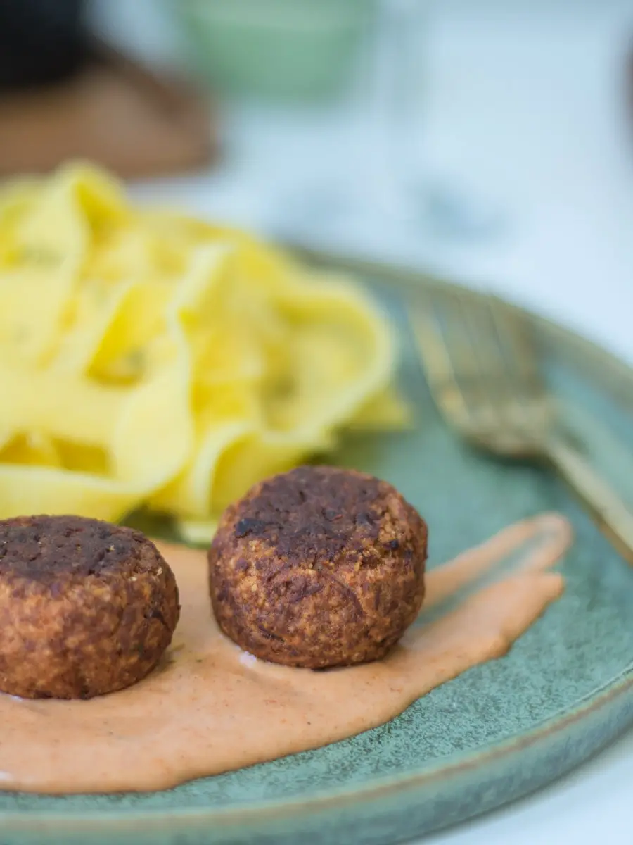 Nahaufnahme von 2 vegetarischen Kürbisbällchen auf einem Klecks Schlemmersauce