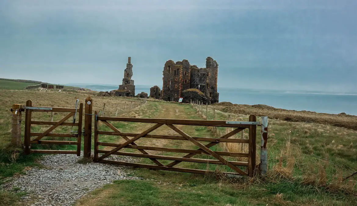 Schottland Rundreise, Blick auf ein Holzgatter und im Hintergrund eine Burgruine
