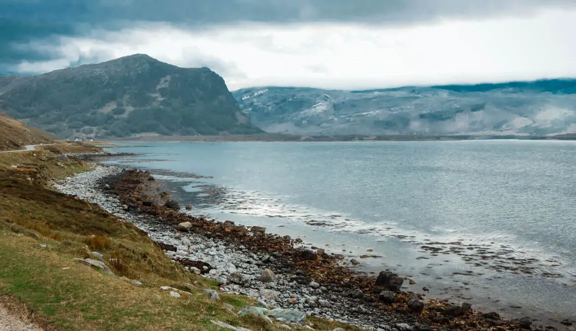 Schottland Rundreise, North Coast 500, Blick auf ein steiniges Meeresufer und daneben eine kurvige Straße