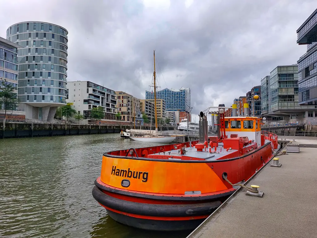 Blick auf die Elbphilharmonie in Hamburg, davor ein orange farbenes Boot
