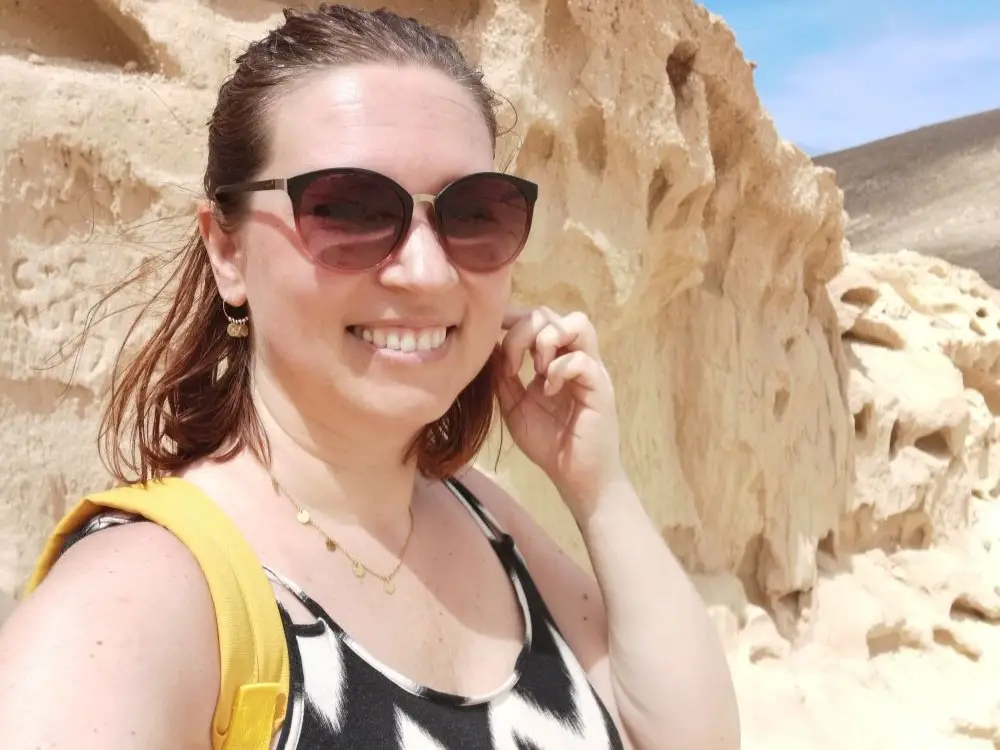 Julia lächelt mit Sonnenbrille in die Kamera, sie genießt ihre Reise alleine auf Fuerteventura.